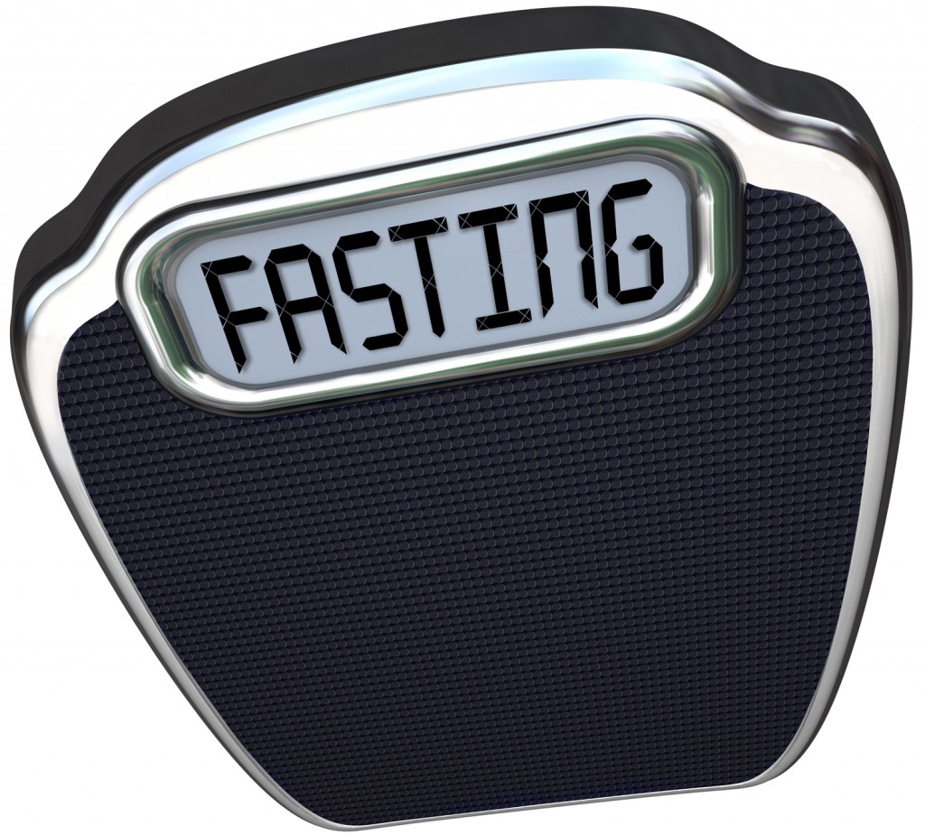 The word Fasting on a digital display of a scale to represent the new 5:2 diet fad or craze in which you reduce calories for two days and eat normally for five